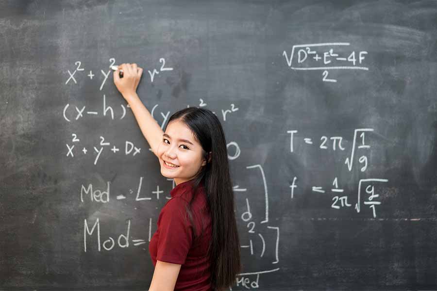 girl writing down maths formulas in tuition class